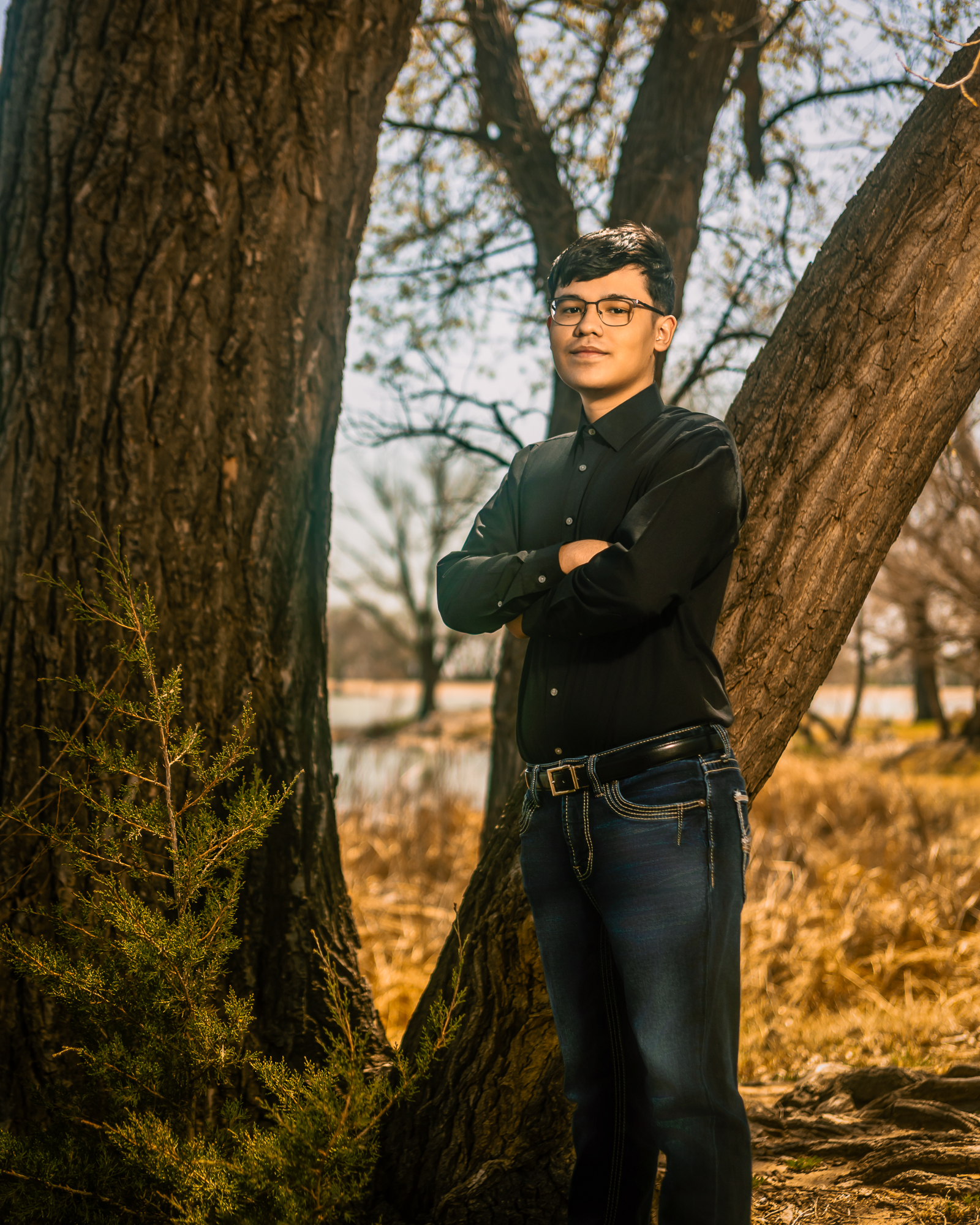 young man standing in front of some trees smiling at the camera